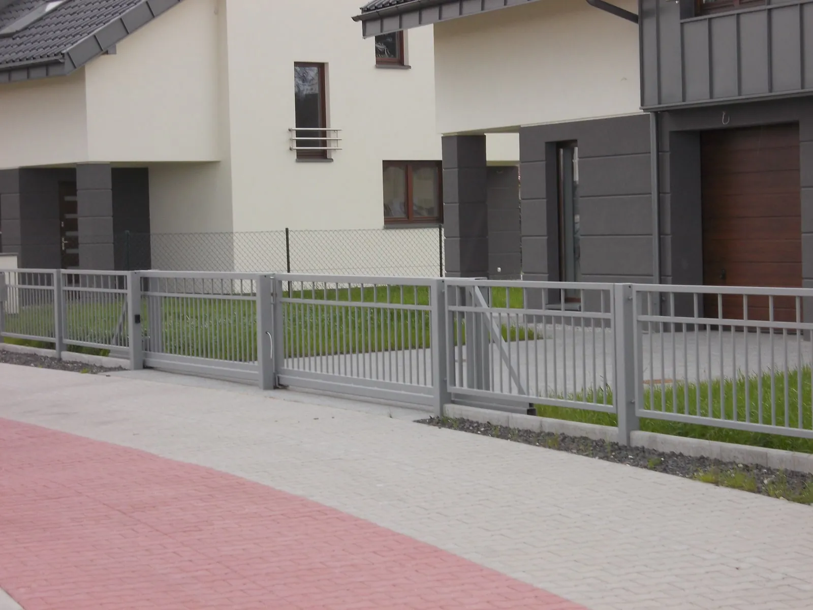 Srebrne ogrodzenie z bramą przesuwną przy nowoczesnym osiedlu