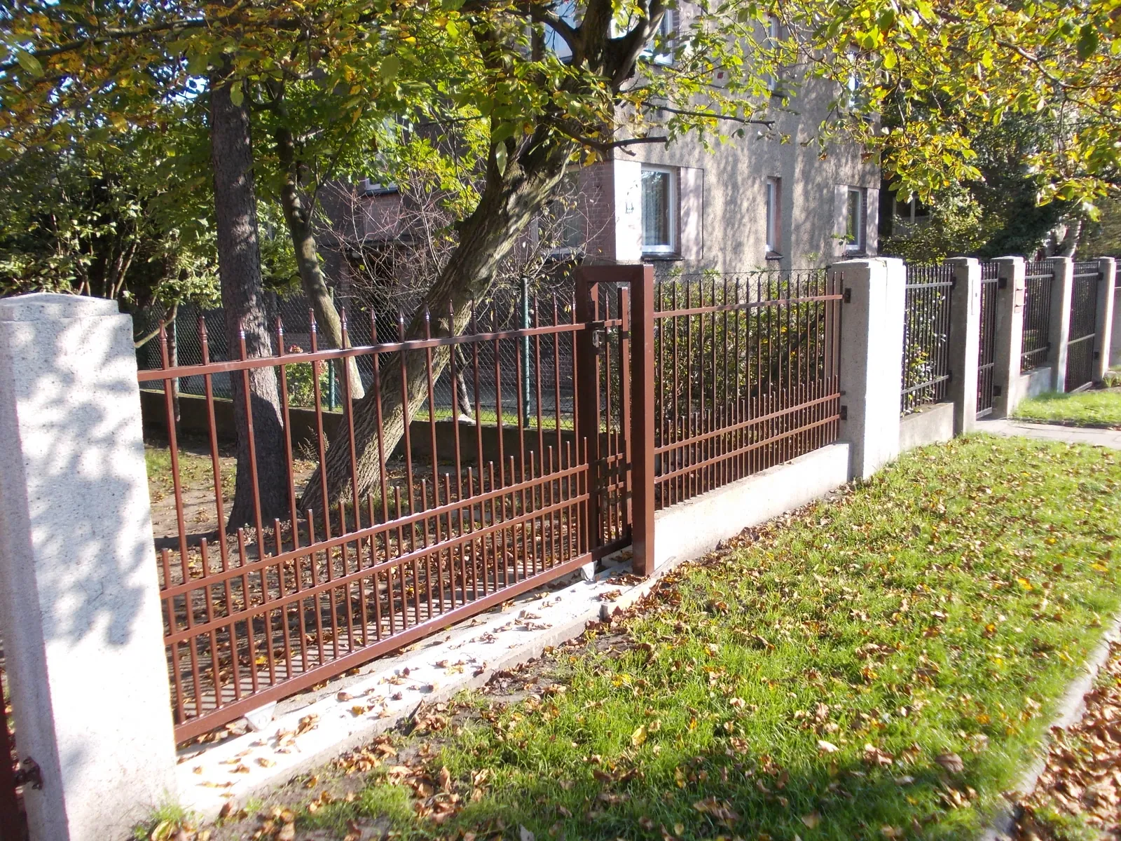 Brązowe ogrodzenie tradycyjne z prętami pionowymi w scenerii jesiennej